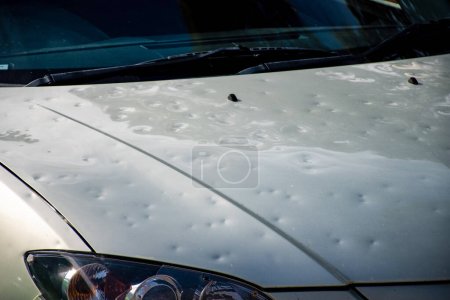 Car hood damaged by major hailstorm hailstones. Car insurance repair dents. Dented car bonnet car after storm weather