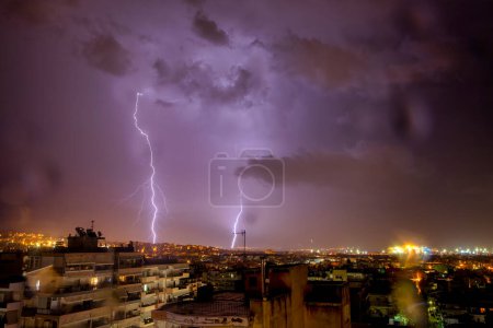 Foto de Vista nocturna de la ciudad bajo la tormenta con el impacto de un rayo. Poderoso rayo durante la tormenta en la ciudad. Nube a tierra relámpago eléctrico detrás. Tesalónica, Grecia del Norte - Imagen libre de derechos