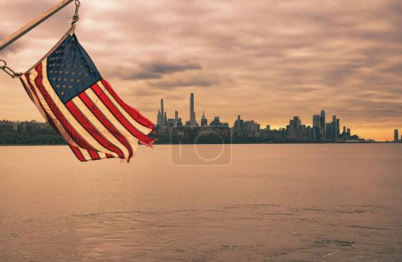 Téléchargez les photos : American flag and scenic view of the Manhattan, New York skyline at sunset as seen from the Hudson River in Edgewater, New Jersey - en image libre de droit