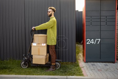 Téléchargez les photos : Homme livrant des marchandises par scooter électrique, équitation près du terminal postal automatique,. Concept de livraison, technologies modernes et mode de vie durable - en image libre de droit