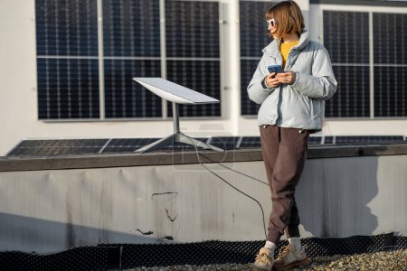 Foto de LVIV, UKRAINE - January, 2023: Woman uses Starlink satellite Internet constellation operated by SpaceX on the roof of her house equipped with solar panels - Imagen libre de derechos