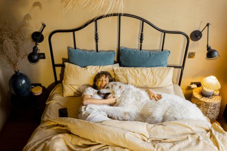Téléchargez les photos : Woman sleeps with her huge and cute dog in cozy bed, view from above. Concept of home coziness and love with pets - en image libre de droit