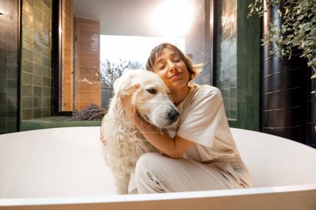 Téléchargez les photos : Young woman hugs with her cute dog in bathtub. Concept of friendship with pets and care - en image libre de droit