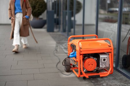 Photo for Electric generator stands on a street and supplies electricity to a shop or cafe during blackout. Concept of backup power supply and blackout - Royalty Free Image
