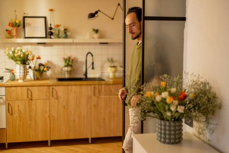 Foto de Hombre lindo mira por la puerta del interior de la cocina moderna. El ocio doméstico y el concepto de interiores del hogar - Imagen libre de derechos