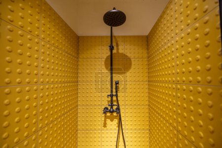 Téléchargez les photos : Cabine de douche en tuiles tactiles jaunes avec robinet noir - en image libre de droit
