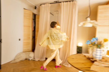 Téléchargez les photos : Studio élégant intérieur dans des tons beiges avec un mouvement flou silhouette féminine marche - en image libre de droit