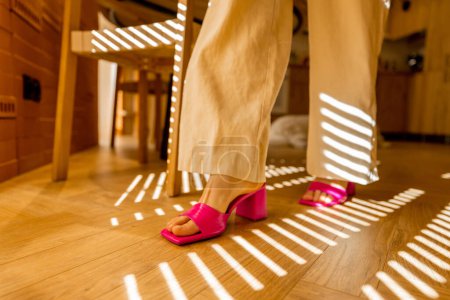 Photo for Woman walking on wooden parquet, close-up. Striped light from the blinds - Royalty Free Image