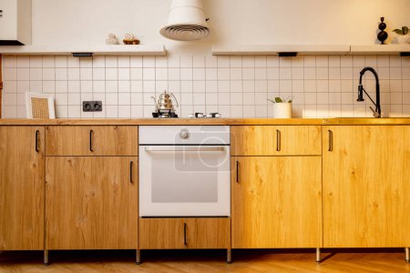 Photo for Kitchen front with oak facades and white tiles on kitchen apron. Interior is equipped with modern equipment - Royalty Free Image