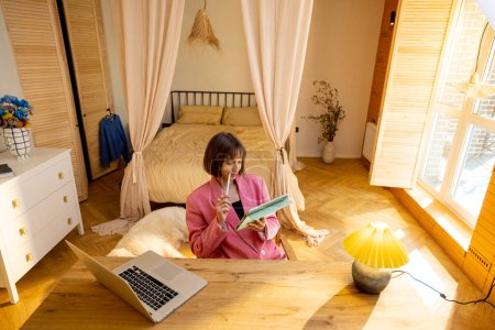 Photo for Young business lady in pink suit works on a digital tablet at cozy home office. Concept of freelance and remote work from cozy home atmosphere - Royalty Free Image