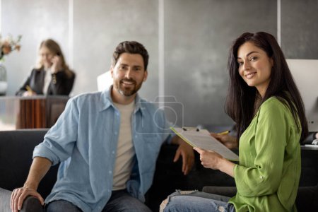 Photo for Portrait of man and woman sitting at the reception desk of modern clinic. Young family visiting hospital - Royalty Free Image