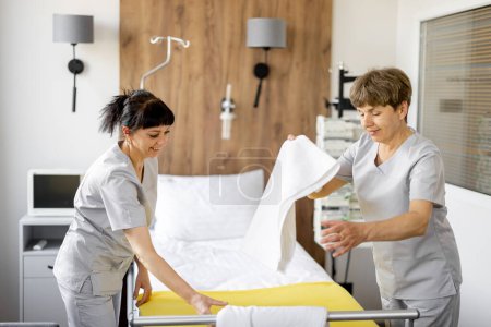 Photo for Maids make the bed in medical ward. Concept of comfortable and modern conditions for the medical stay of patients - Royalty Free Image