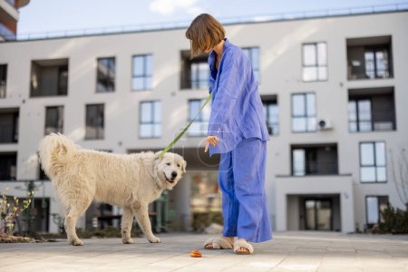 Photo for Woman points finger on dogs poop, while walking with pet in the yard of an apartment building. Concept of cleaning up after pets in public place - Royalty Free Image