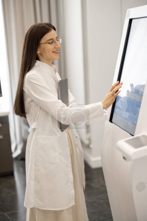 Photo for Portrait of a doctor touching the screen of body analyzer machine at beauty salon. Concept of non-invasive and quick body research for beauty industry - Royalty Free Image