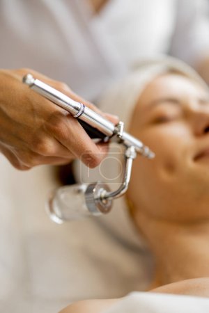 Téléchargez les photos : Jeune femme recevant de l'oxygène en mésothérapie sur son visage, vue rapprochée d'en haut. Concept de traitement non invasif et revitalisant de la peau - en image libre de droit