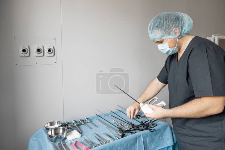 Photo for Surgeon takes medical instruments starting surgery in operating room. Sterile medical instruments are laid out on the table - Royalty Free Image
