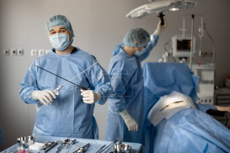 Foto de Retrato de un cirujano de uniforme con instrumentos médicos estériles listo para cirugía en quirófano. Concepto de tratamiento invasivo - Imagen libre de derechos