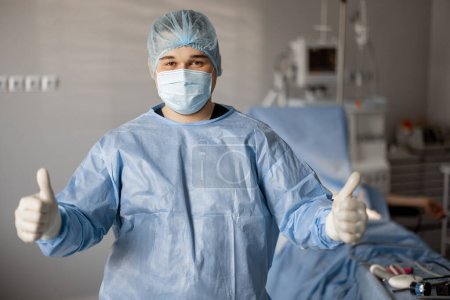 Foto de Retrato de un cirujano confiado en uniforme de pie en quirófano listo para tratamiento invasivo - Imagen libre de derechos
