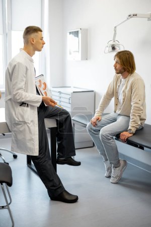 Foto de Paciente masculino en consulta con gastroenterólogo en consultorio médico. Doctor con el hombre durante la consulta médica - Imagen libre de derechos