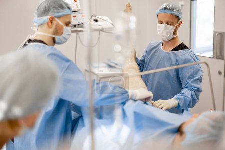 Photo for Preparation for surgical operation. Surgeons covers the patient with a sterile drape - Royalty Free Image