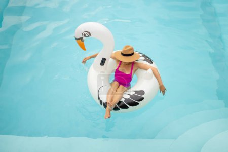 Téléchargez les photos : Femme flotte sur le jouet gonflable de flamant rose, reposant à la piscine, vue d'en haut. Concept de vacances d'été - en image libre de droit