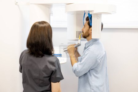 Foto de Paciente masculino durante una radiografía de la mandíbula con un escáner moderno en la clínica. Departamento estomatológico y concepto de diagnóstico - Imagen libre de derechos