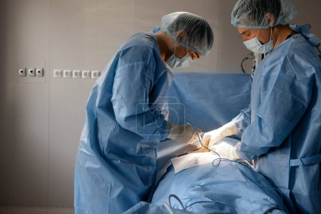Foto de Dos cirujanos operan el área abdominal de un paciente. Concepto de operación real e intervención quirúrgica - Imagen libre de derechos