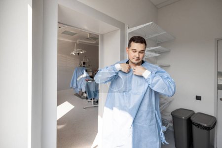 Téléchargez les photos : Portrait d'un chirurgien fatigué enlevant son uniforme après une intervention chirurgicale difficile, tout en quittant une salle d'opération - en image libre de droit