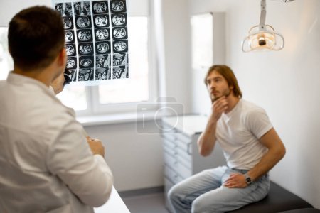 Téléchargez les photos : Homme sur rendez-vous médical avec l'urologue, le médecin montre une radiographie du bassin des patients. Concept de santé masculine - en image libre de droit