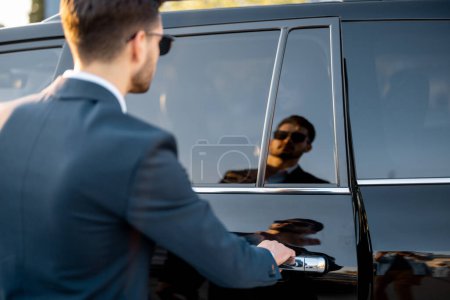 Foto de Retrato de un hombre de negocios que abre la puerta del vehículo, reflejo en el coche - Imagen libre de derechos