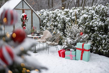 Téléchargez les photos : Beautifully decorated backyard with gift boxes, christmas tree and wreaths on winter holidays at snowy backyard - en image libre de droit