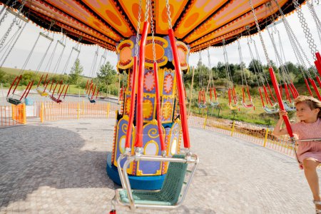 Téléchargez les photos : Enfants chevauchant sur carrousel d'amusement coloré tout en visitant le parc d'attractions pendant des vacances d'été - en image libre de droit