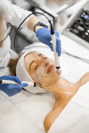 Foto de Mujer joven durante el procedimiento de microcorriente facial, vista de cerca en la cara y electrodos especiales. Faciales de microcorriente para el efecto de elevación, tratamiento de la piel de belleza - Imagen libre de derechos