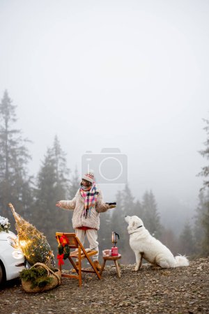 Photo for Young woman relaxes and enjoys calm on nature, while sitting with her dog at picnic during winter holidays in mountains. Image with copy space - Royalty Free Image