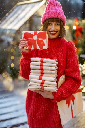 Foto de La mujer sostiene la pila de bolsas de lino con la impresión del arco de Año Nuevo, primer plano. Concepto de decotación festiva para las vacaciones de invierno - Imagen libre de derechos