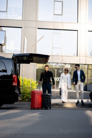 Téléchargez les photos : Chauffeur ou concierge aide un couple d'affaires à transporter leurs valises en taxi minibus de l'hôtel. Concept de voyage d'affaires et de service de transport - en image libre de droit
