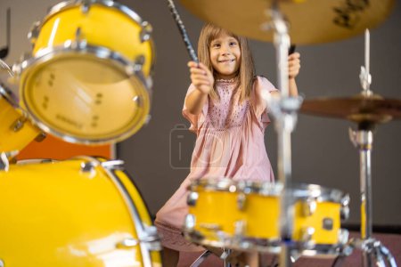 Photo for Girl playing on a real drums, having fun while visiting a science museum - Royalty Free Image
