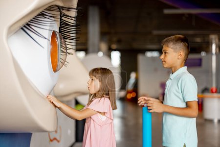 Foto de Los niños miran a un modelo de ojos grandes, educando y divirtiéndose en un museo de ciencias. Concepto de aprendizaje de los niños a través del entretenimiento - Imagen libre de derechos