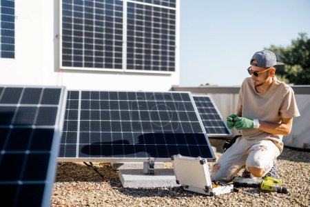 Foto de Hombre instalando paneles solares en el techo de su casa. Concepto de energía renovable y sostenibilidad. Idea de instalar paneles para los hogares - Imagen libre de derechos