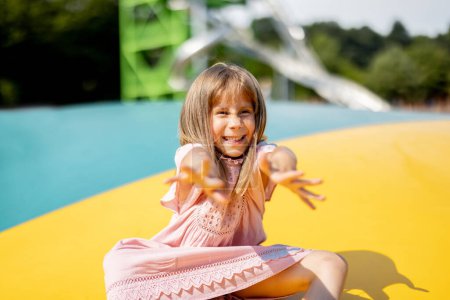 Téléchargez les photos : Portrait d'une petite fille mignonne qui s'amuse à visiter un parc d'attractions pendant les vacances d'été - en image libre de droit