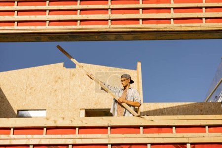 Photo for Man as builder or carpenter on construction site of a wooden frame house - Royalty Free Image
