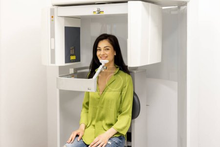 Foto de Mujer sonriente durante una radiografía o una tomografía computarizada de la cabeza en un consultorio médico - Imagen libre de derechos