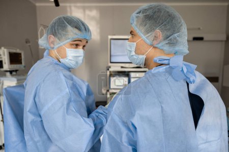 Photo for Two surgeons performs minimally invasive procedure with endoscopes, looking on monitor in operating room. Concept of endoscopic-computer assisted treatment - Royalty Free Image