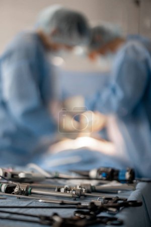 Téléchargez les photos : Traitement chirurgical en cours, gros plan sur les outils médicaux et les chirurgiens opérant derrière - en image libre de droit