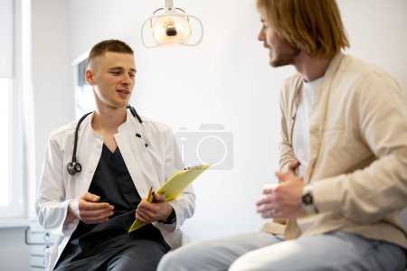 Foto de Paciente masculino en consulta con gastroenterólogo en consultorio médico. Doctor con el hombre durante la consulta médica - Imagen libre de derechos