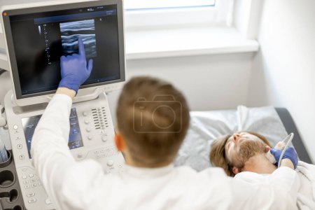 Photo for Young guy during an ultrasound diagnosis of the carotid artery. Concept of ultrasound diagnostics and mens health. Idea of examination of cardiovascular diseases - Royalty Free Image
