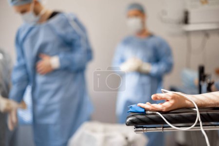 Foto de Los pacientes se arman con un oxímetro de pulso acostado en la mesa de operaciones durante la cirugía. Concepto de monitorización de la condición de los pacientes durante la cirugía - Imagen libre de derechos