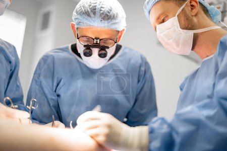 Photo for Surgeon with microscope glasses during an operation. Concept of real surgery and invasive treatments - Royalty Free Image