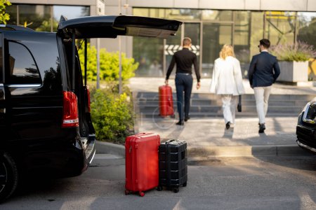 Téléchargez les photos : Chauffeur ou concierge aide un couple d'affaires à transporter leurs valises au bureau ou à l'hôtel à partir d'un taxi minibus. Concept de voyage d'affaires et de service de transport - en image libre de droit