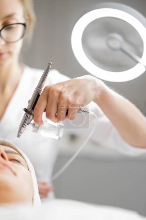 Foto de Joven cosmetólogo realiza mesoterapia de oxígeno en la cara de las mujeres en el salón de belleza. Concepto de tratamiento no invasivo y revitalizante de la piel - Imagen libre de derechos